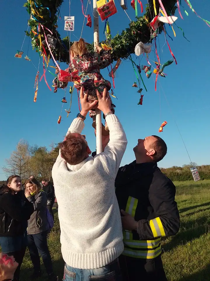 Kleinkind erklimmt den Maibaum mit der Unterstützung der Feuerwehr